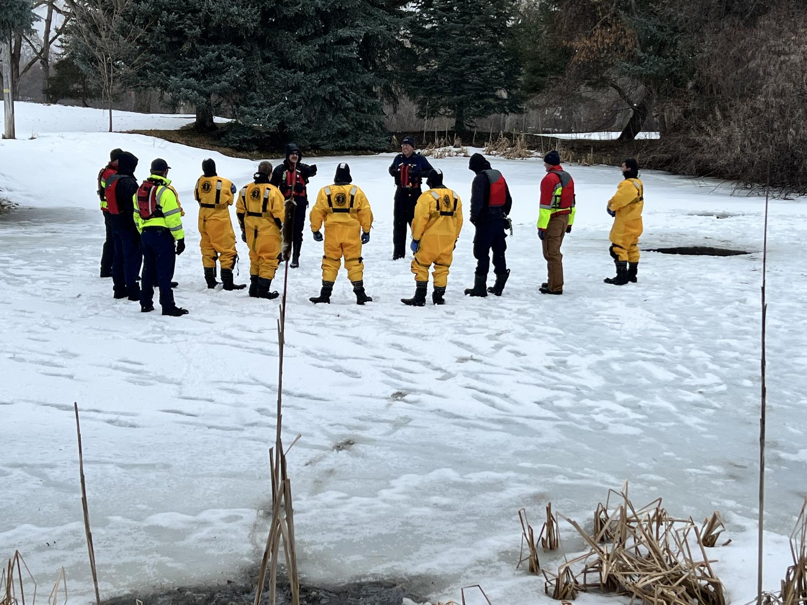 Ice rescue team briefing on frozen lake with full gear